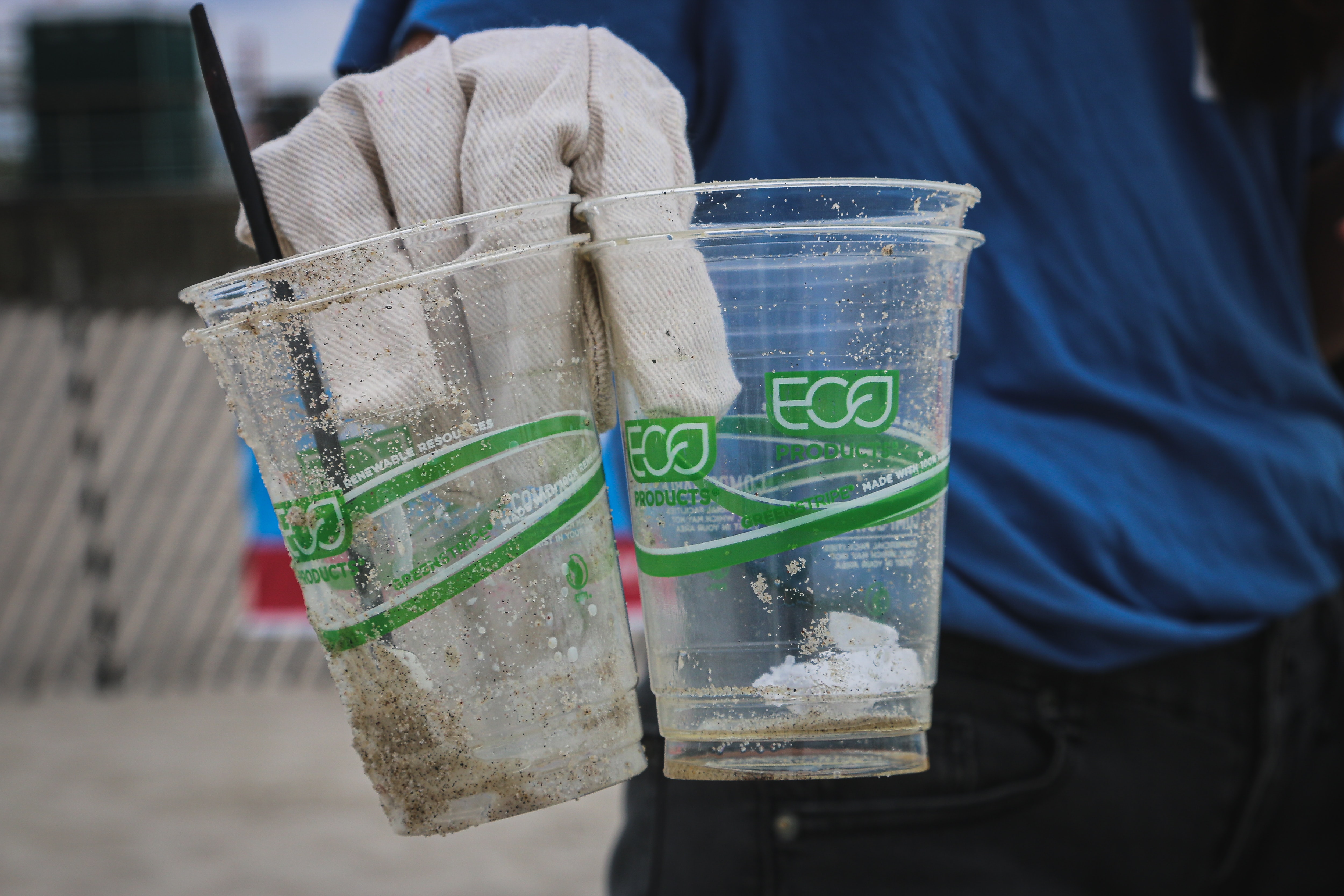 Two clear plastic cups about to be recycled being held